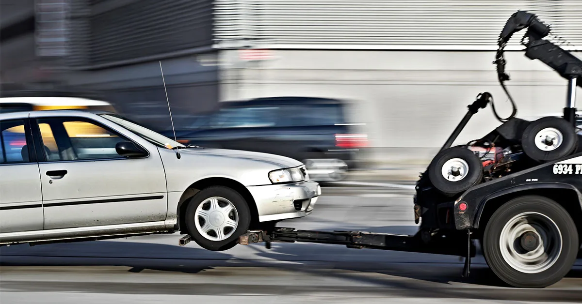 Car being towed on two wheels from a tow truck.