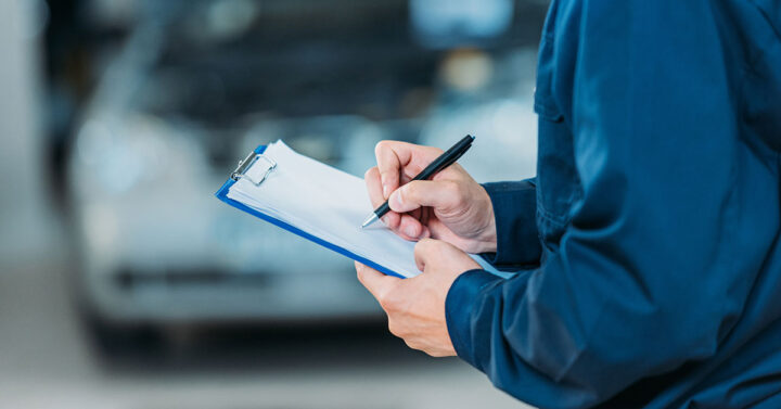 Vehicle assessor filling out form on clipboard.