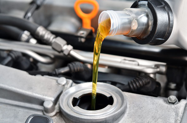 Engine oil being poured into reservoir in car engine bay