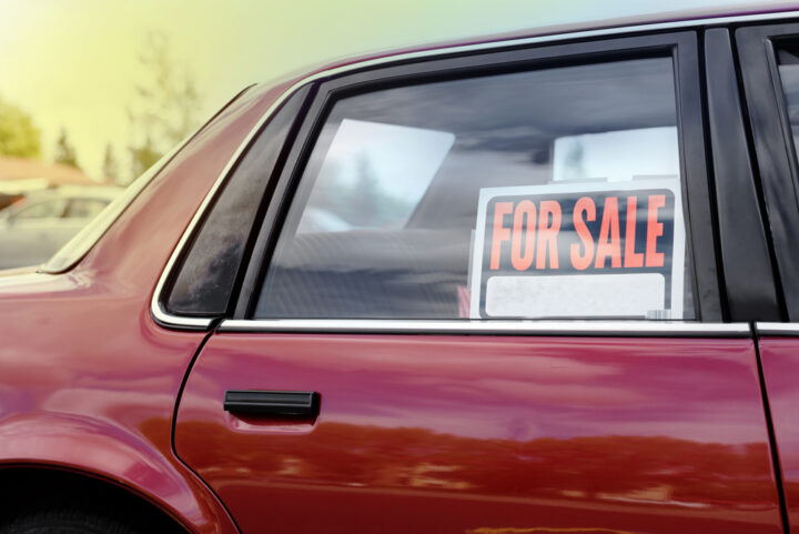 Shiny red car with for sale sign, parked in neighborhood