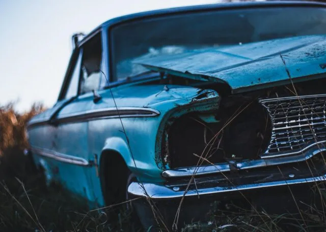 An old scrap car in an empty lot.