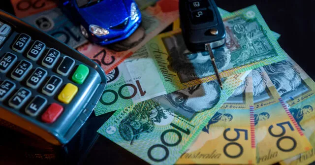 Pile of money on the table with a car key and payment processing machine