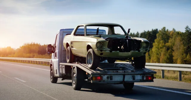 Old vehicle being towed away on a tow truck