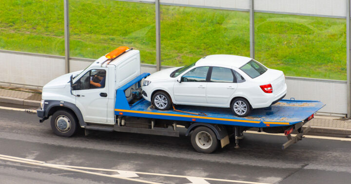 Unwanted white sedan being towed away after being purchased for a great price